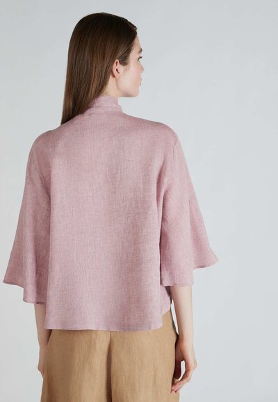 Kimono in lino rosa chiaro con colletto alto, maniche svasate e vestibilità morbida, che presenta un tessuto testurizzato e un design semplice.