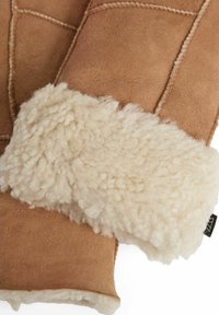 Lysebrune ruskindshandsker med en blød uldforing og manchet. Har synlige sømme og en tekstureret, blød lammeskindspynt.