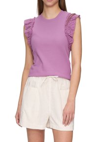 Lila mouwloze top met gerimpelde laken schouders, gecombineerd met witte linnen shorts met een elastiche taille en voorzakken.