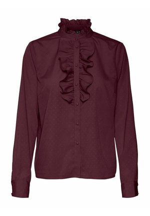 Blouse longue manches violette foncée avec col montant à volants et devant boutonné avec un détail de volant central.