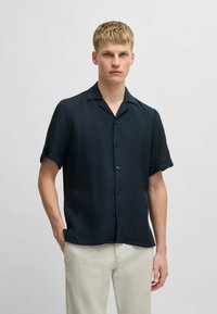 Korte mouwen, knoopsluiting overhemd in donker marineblauw stof met een gladde textuur, voorzien van een afgeknipte kraag en een ontspannen pasvorm.