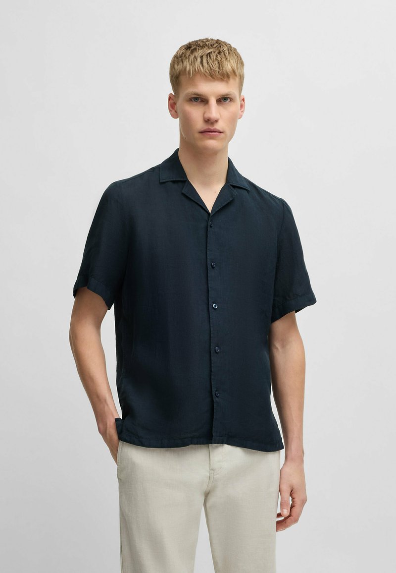 Korte mouwen, knoopsluiting overhemd in donker marineblauw stof met een gladde textuur, voorzien van een afgeknipte kraag en een ontspannen pasvorm.
