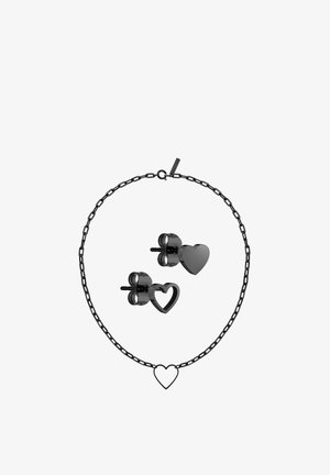 Collier avec pendentif en forme de cœur en métal noir avec boucles d’oreilles assorties, un cœur plein et un cœur creux sur fond blanc.