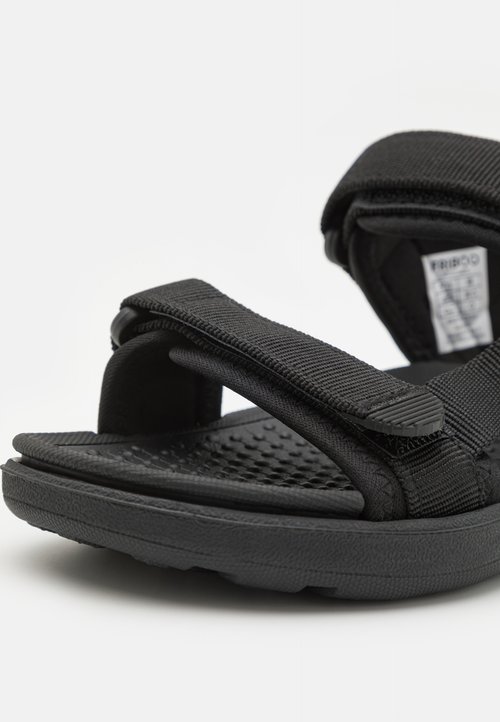 Sandalias negras con suelas de goma texturizadas, correas de tela ajustables y una plantilla acolchada para mayor comodidad y soporte.