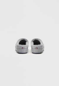 Papuci gri dintr-un material moale, cu interior confortabil, design cu spatele deschis și un mic accent tricolor lângă călcâi; talpă plată pentru confort.