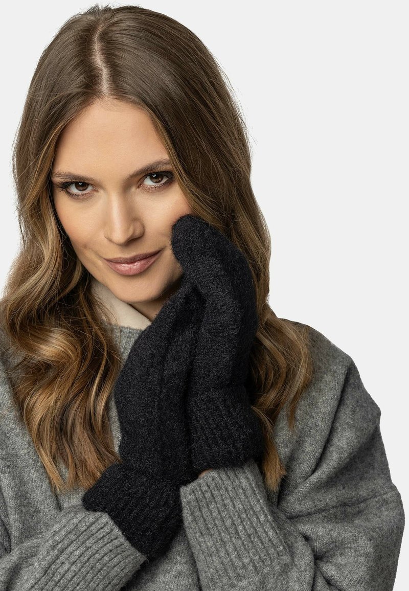 Mittens in lana nera con una finitura texture, polsini a coste e una vestibilità aderente. Il modello indossa un maglione grigio, che completa i guanti.