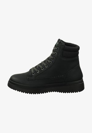 Stivale alla caviglia in pelle nera con lacci grigi, suola in gomma e colletto imbottito, con un logo discreto sul lato. Superficie strutturata.