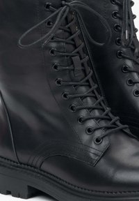 Czarne skórzane buty na sznurówki o gładkiej fakturze, z zewnętrznym zamkiem błyskawicznym, metalowymi oczkami i wytrzymałą podeszwą.