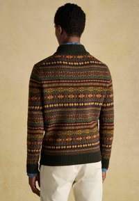 Kötött pulóver, amely sötétzöld, barna, narancs és arany színű, többszínű geometrikus mintával rendelkezik, bordás nyakkal és mandzsettával.