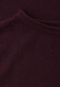 Vínová pletená tkanina s hladkou texturou a mírným pružením, zobrazující jemný vzor tenkých vodorovných linií a složený okraj.