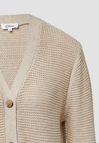 Beżowy sweter dzianinowy z dekoltem w serek, długimi rękawami i pojedynczym zapięciem na drewniany guzik, z teksturowanym materiałem i prążkowanymi brzegami.