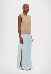 Beige strikket ermløs vest med knappestolpe og lysblå denimmaxiskjørt med sidesliss, teksturert stoff og avslappet passform.