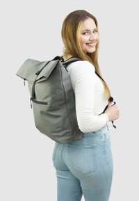 Grijze waterdichte rugzak met een oprol ontwerp, verstelbare schouderbanden en een ritssluitingszak aan de voorkant. Gladde textuur, moderne en functionele vorm.