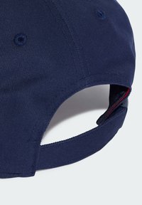 Námornícka modrá čiapka s textúrovanou tkaninou, zakriveným šiltom a nastaviteľným remienkom na zadnej strane s kontrastným červeným akcentom vo vnútri.