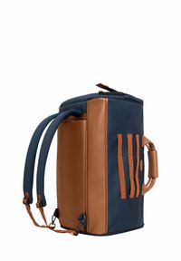Sac à dos marron et marine avec une forme structurée, en cuir texturé et tissu, avec des poignées renforcées et des bretelles ajustables. Il est doté de sangles horizontales.