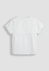 Camiseta de algodón blanca con mangas cortas y acampanadas y panel trasero fruncido. Textura suave con escote redondeado y corte casual.