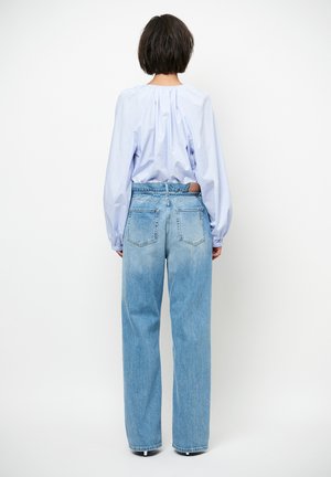 Lichtblauwe blouse met lange mouwen en een geplooide achterkant, gecombineerd met lichtgewassen, high-waisted spijkerbroek met een ontspannen pasvorm en een rafelige zoom.