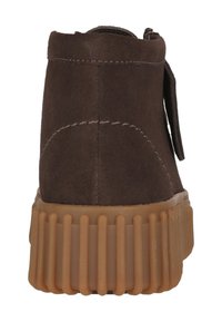 Bruine suède enkellaars met een dikke, geribbelde zool van rubber. Voorzien van een ritssluiting en gestikte details aan de achterkant.