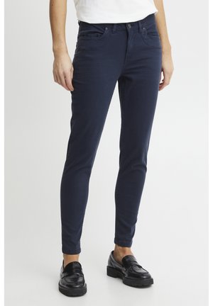 Navy blue slim-fit jeans made of soft denim, featuring five pockets, belt loops, and subtle stitching details. Matched with black loafers.
