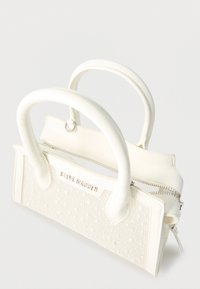 Λευκή τσάντα Steve Madden με υφή στο μπροστινό μέρος, δύο στρογγυλεμένες λαβές και κλείσιμο με φερμουάρ στο πάνω μέρος, πάνω σε απλό φόντο.