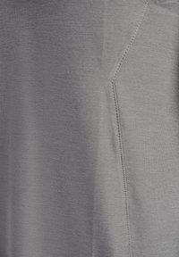 Graues T-Shirt mit glatter Textur, das über eine vertikale Nahtdetail an der Seite verfügt. Hergestellt aus einem leichten, dehnbaren Stoff.