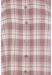 Gros plan sur un tissu à carreaux marron et rose avec cinq boutons mauves alignés au centre, montrant la texture détaillée et la couture des boutons.