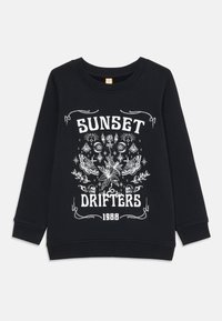 Felpa nera con un motivo grafico bianco che presenta il testo "SUNSET DRIFTERS 1988" e dettagli floreali e di farfalle. Maniche a costine.