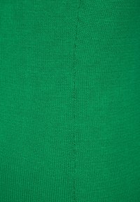 Zelená pletená látka s hladkou texturou, s hustým vazebním vzorem a jednotnou barvou. Šev se táhne vertikálně uprostřed.