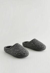 Graue Wollschlappen mit einer weichen, strukturierten Oberseite und schwarzen Gummisohlen. Abgerundete Zehenform und ein einfaches Slip-On-Design für bequemes Tragen.