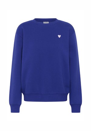 Kobalti zila sporta jaka, kas izgatavota no mīksta auduma, ar apaļu kakla izgriezumu, ribotiem aproču galiem un mazu izšūtu rozā sirdi uz krūtīm.