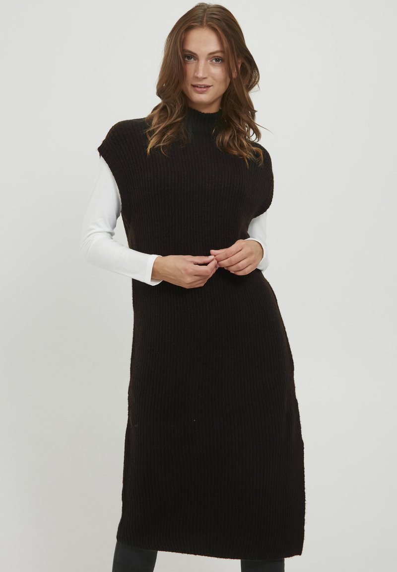 Robe en tricot noire avec col montant, design sans manches et texture côtelée. Présente une silhouette droite et une coupe au genou.