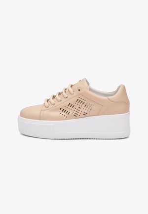 Zapatilla deportiva de plataforma beige con patrones geométricos perforados, cordones beige y una suela blanca gruesa, mostrada desde el lado izquierdo.