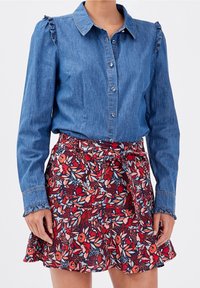 Denim blouse met geschulpte schouderaccenten, gecombineerd met een bloemenpatroon, flared minirok in rood, roze en marineblauw.