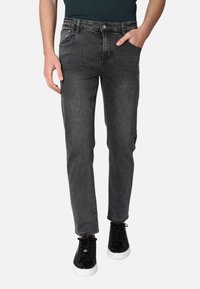 Jeans grigi scuri in denim, con design slim fit, cinque tasche e chiusura con bottone, abbinati a sneaker nere.
