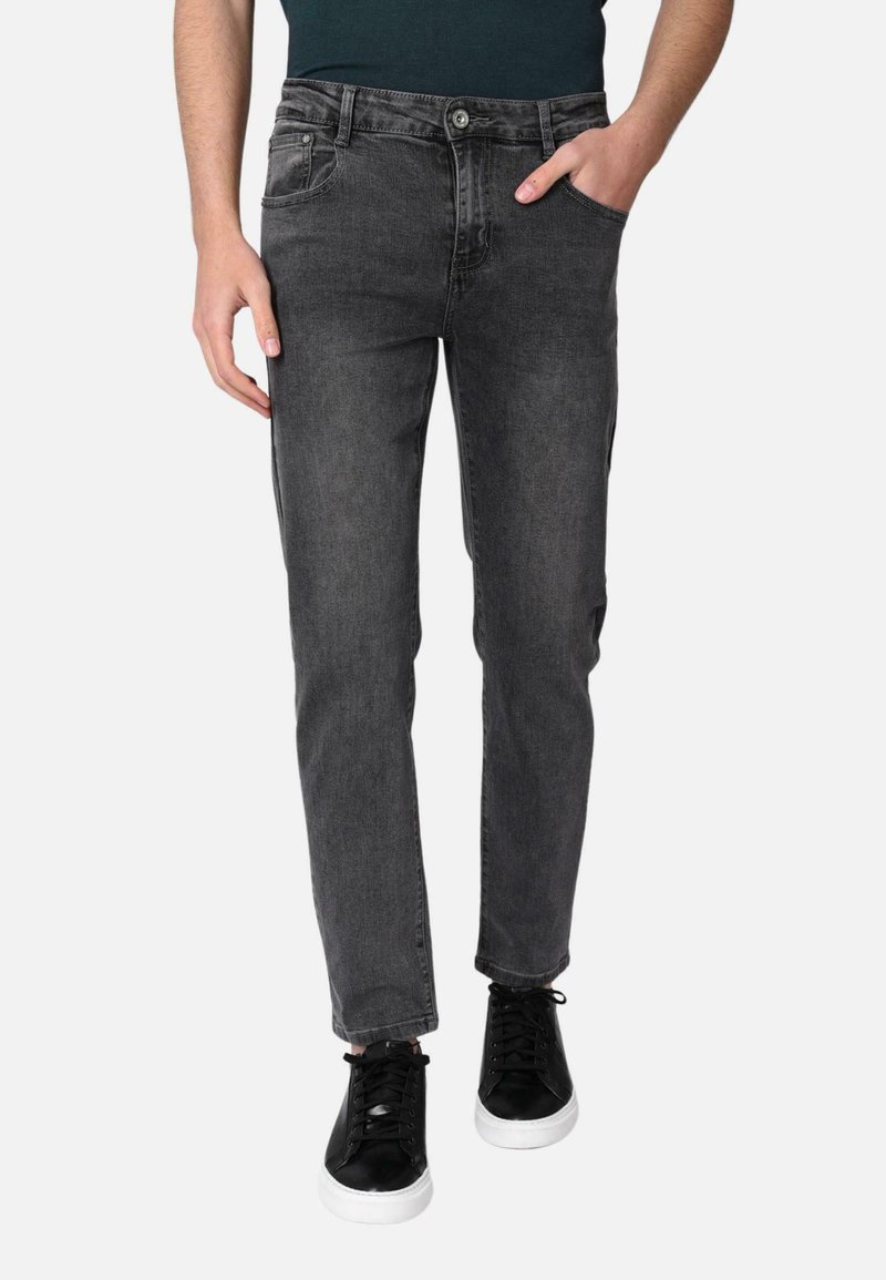 Jeans grigi scuri in denim, con design slim fit, cinque tasche e chiusura con bottone, abbinati a sneaker nere.