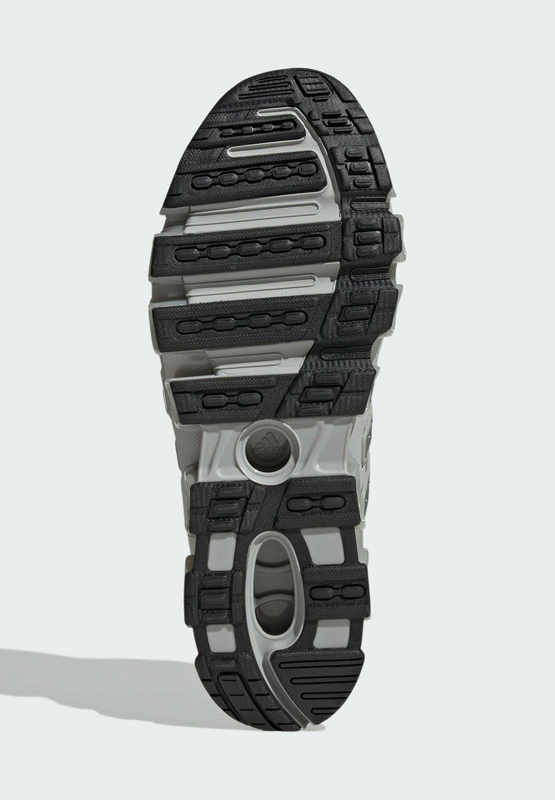 Sorte og grå sneaker-sål med et tekstureret mønster, fremhævede stødpuder og en central åbning for støtte.