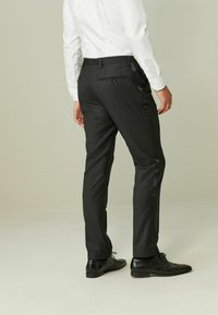 Sorte skræddersyede bukser med en glat tekstur, der har en slank pasform og satin accenter på siden; parret med sorte dress shoes.
