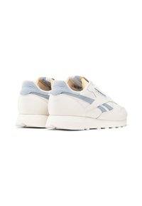 Un paio di sneaker Reebok off-white con accenti in suede azzurro chiaro, esposte di lato e da dietro su uno sfondo bianco.