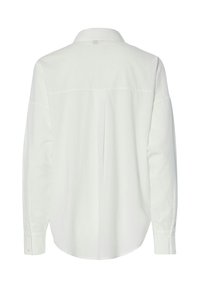 Camisa blanca de manga larga con cuello, que presenta una costura en el yugo trasero y sutiles detalles de pliegues. Textura suave y puños con botones clásicos.