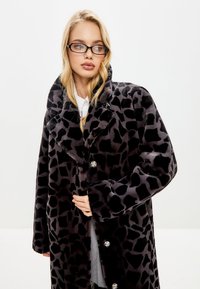 Nepvacht leopard-print jas in zwart en grijstinten, met een grote kraag, knoopsluitingen en lange mouwen.