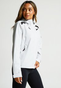 Light grey jacket with a hood, zippered front, and black accents on shoulders. Features side pockets and a fitted design. Smooth texture.