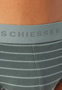Grau gestreifte Unterwäsche mit einer weichen Textur und einem elastischen Bund mit Markendruck, der "SCHIESSER" in einem dezenten Print zeigt.