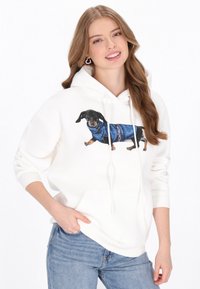 Sudadera con capucha blanca que presenta un dachshund impreso con un suéter azul. Tejido suave, capucha con cordón ajustable y detalle de bolsillo delantero.