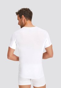 White short-sleeve t-shirt with a simple design, round neckline, and fitted shape. Material appears soft and slightly sheer.