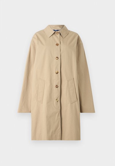 Casaco de algodão bege com gola, fecho de seis botões, dois bolsos frontais e uma silhueta solta. Textura suave com detalhes mínimos.