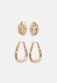 Pendientes en tono dorado que presentan formas texturizadas y onduladas. Incluyen aros de clip esculturales y un diseño de aro abierto con un acabado martillado.