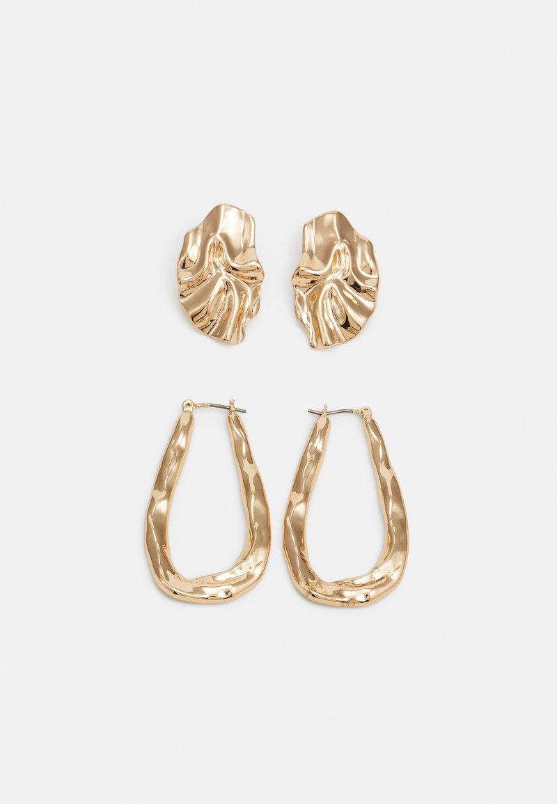 Pendientes en tono dorado que presentan formas texturizadas y onduladas. Incluyen aros de clip esculturales y un diseño de aro abierto con un acabado martillado.