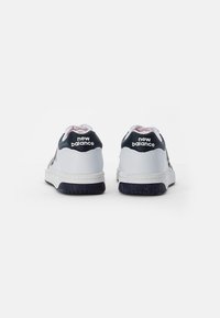 Białe trampki z granatowymi akcentami, miękki materiał górny, kontrastowe różowe detale oraz teksturowane gumowe podeszwy z brandingiem "new balance".