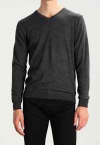 Ciemnoszary sweter v-neck z miękkiego materiału, z długimi rękawami i dopasowanym krojem, w połączeniu z czarnymi spodniami.