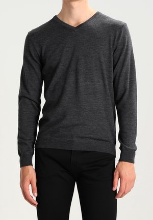 Pull à col en V gris foncé fait en matériau doux, présentant des manches longues et un design ajusté, associé à un pantalon noir.